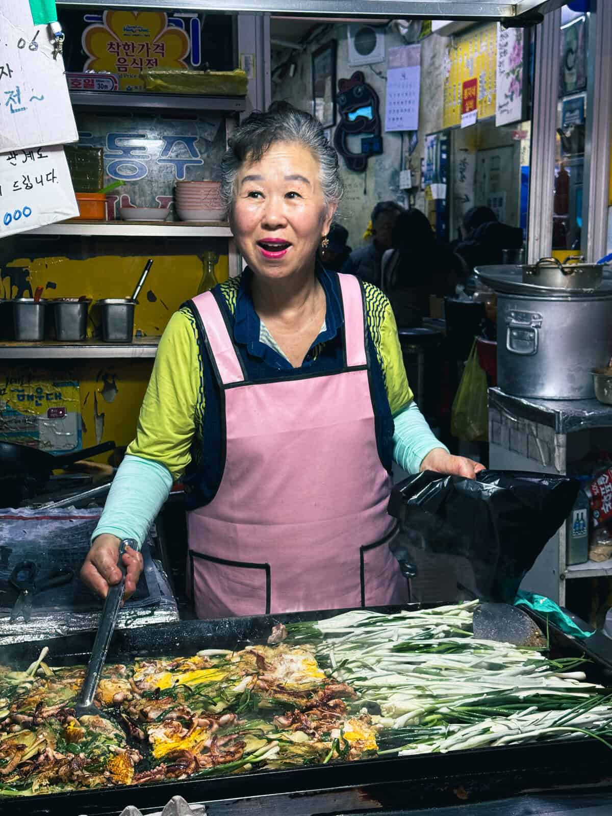 women business owner in pink apron cooking in Busan south korea